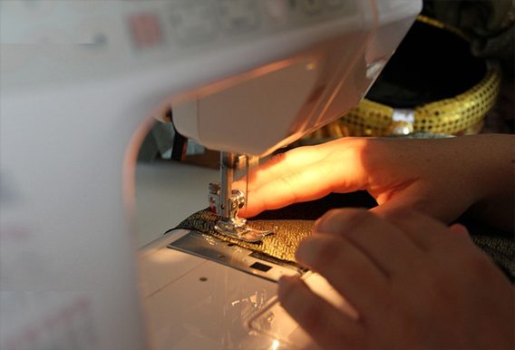 Hands guiding suit fabric through a sewing machine